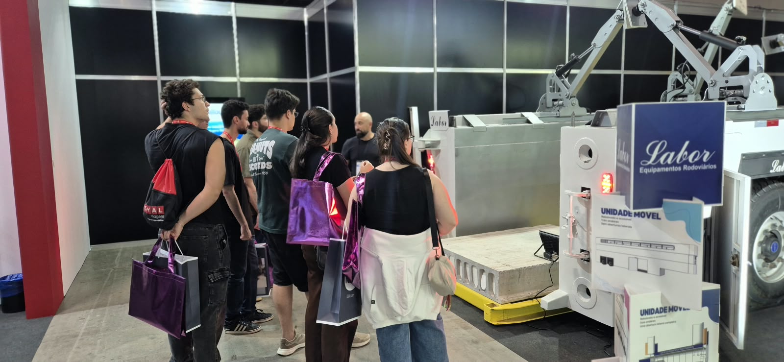 Grupo de visitantes conhecendo a Concrete Loader no stand